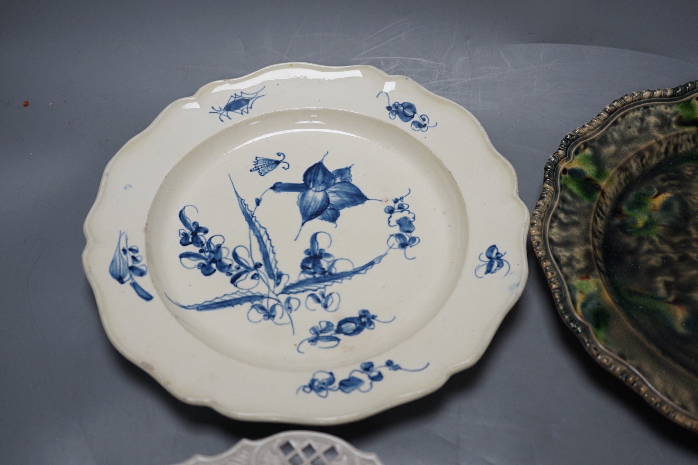 A Staffordshire salt glaze plate with pierced border, a Staffordhire tortoiseshell painted plate, a creamware underglaze blue plate and a Dutch delft plate, salt glazed plate 21 cms diameter